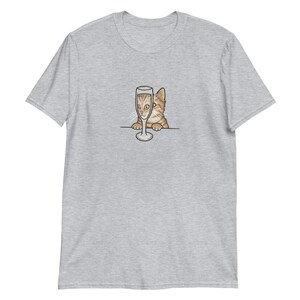 May include: A gray t-shirt with a cartoon image of a cat peeking over a champagne glass.