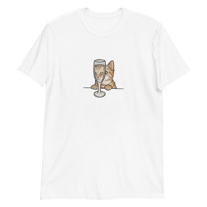 May include: A white t-shirt with a cartoon image of a cat peeking over the top of a champagne glass.