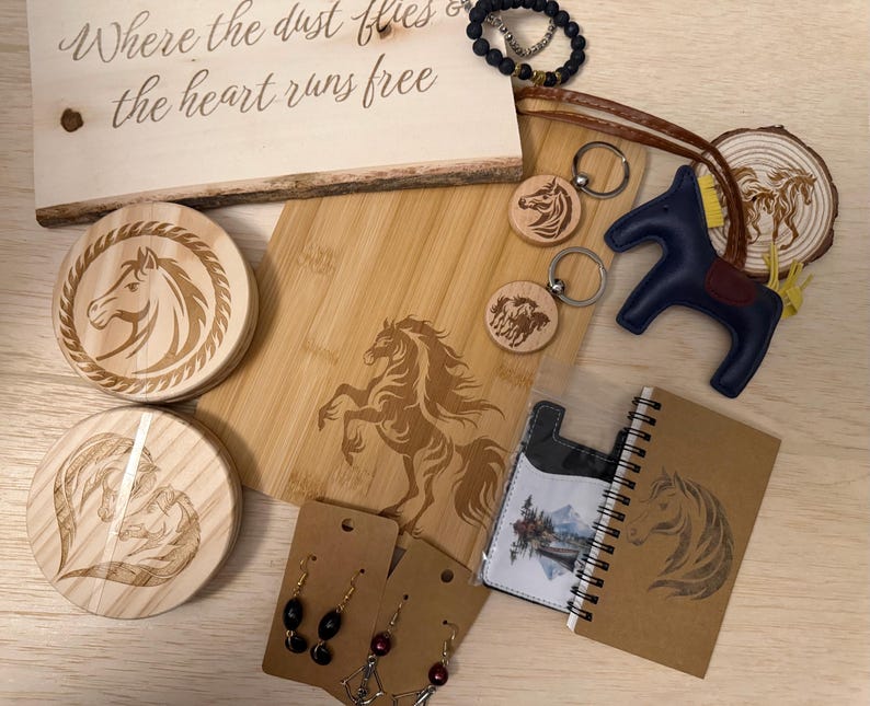 May include: A collection of horse-themed items, including wooden coasters, a cutting board, keychains, earrings, a leather horse figurine, and a notebook. The wooden sign reads "Where the dust flies & the heart runs free."