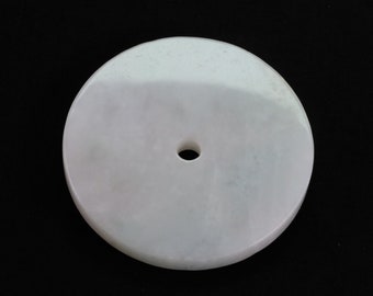 May include: A white round disc with a hole in the center. The disc has a smooth, polished surface.