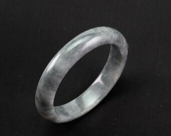 Könnte beinhalten: Ein graues Jade-Armband mit glatter, polierter Oberfläche.