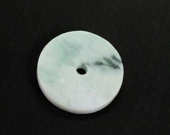 May include: A white jade pendant with a hole in the center. The jade has a light green and gray marbling pattern.