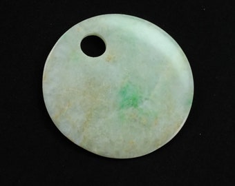May include: A round, light green jade pendant with a hole in the center. The pendant has a mottled appearance with white and brown markings.
