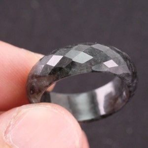 May include: A black faceted gemstone ring. The ring is made of a smooth, polished stone with a faceted design.