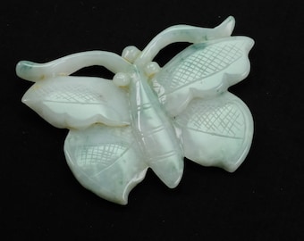 May include: A carved jade butterfly pendant, featuring a light green colour and intricate details. The butterfly has a delicate, almost translucent appearance.