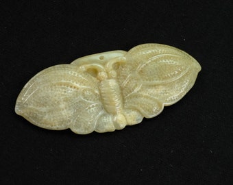 May include: A carved jade butterfly pendant in a light beige colour. The butterfly has detailed wings and a body with a hole at the top for hanging.