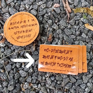 Może przedstawiać: Trzy prostokątne karty i okrągły podkładka z brązowym starożytnym tekstem pismem klinowym. Na kartach napisano "Either take it or not, and get lost! Ea-nasir." Na podkładce napisano "You'll learn that around here I will not accept poor quality copper!"