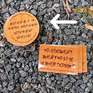 Puede incluir: Posavasos y tarjetas de color marrón anaranjado con texto antiguo. El posavasos redondo dice: "Aprenderás que por aquí, no aceptaré cobre de mala calidad". Las tarjetas rectangulares dicen: "¡Tómalo o no, y piérdete! - Ea-nasir."