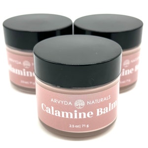 May include: Three jars of pink calamine balm with black lids. The label reads "Arvyda Naturals Calamine Balm 2.5 oz | 71 g".