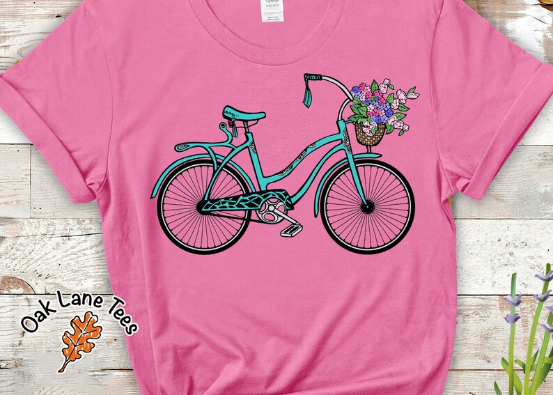 Puede incluir: Una bicicleta azul turquesa con una cesta de flores en el manillar. La bicicleta tiene un fondo rosa.