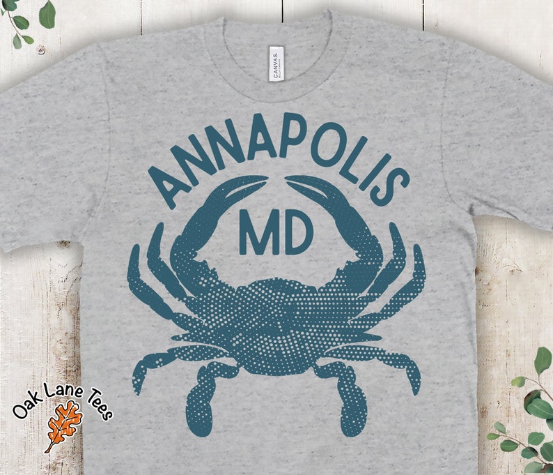 May include: A grey t-shirt with a blue crab design and the text "ANNAPOLIS MD" printed on the front.