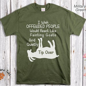 Może przedstawiać: Zielona koszulka w kolorze wojskowym z napisem "I Wish Offended People Would React Like Fainting Goats And Quietly Tip Over" oraz białą grafiką omdlewającej kozy. Koszulka ma okrągły dekolt.