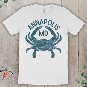 May include: White t-shirt with a blue crab graphic and the text "Annapolis MD".