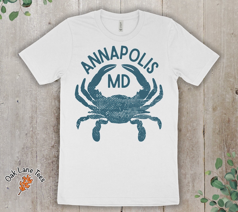 May include: White t-shirt with a blue crab graphic and the text "Annapolis MD".
