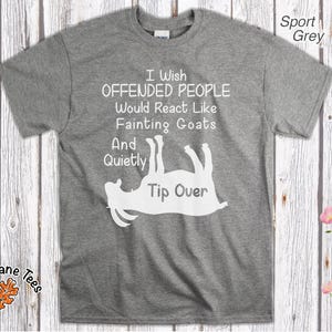 Może przedstawiać: Szara koszulka sportowa z białym napisem "I Wish Offended People Would React Like Fainting Goats And Quietly Tip Over". Koszulka posiada białą grafikę omdlewającej kozy. Nazwa marki "Oak Lane Tees" jest wydrukowana na dole po lewej stronie.