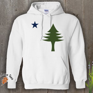 Pu&ograve; includere: Felpa con cappuccio bianca con un pino verde e una stella blu sul davanti. Il testo "Oak Lane Tees" &egrave; sulla manica sinistra.
