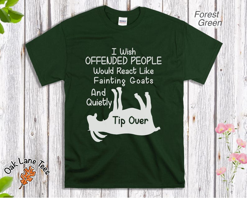 Może przedstawiać: Leśnozielona koszulka z białym napisem: "I Wish Offended People Would React Like Fainting Goats And Quietly Tip Over." Poniżej tekstu znajduje się biała grafika przedstawiająca kozę. Koszulka jest na drewnianym tle.