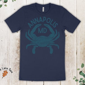 May include: Navy blue t-shirt with a teal blue crab graphic and the text "ANNAPOLIS MD".