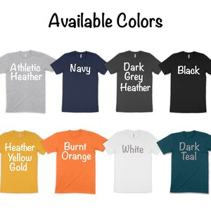 May include: A selection of t-shirts in various colors, including athletic heather, navy, dark grey heather, black, heather yellow gold, burnt orange, white, and dark teal. The t-shirts are all short-sleeved and have a crew neck.