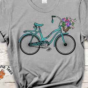 Puede incluir: Una bicicleta azul turquesa con una cesta de flores en el manillar. La bicicleta tiene un sill&iacute;n negro y neum&aacute;ticos negros. Las flores son rosas, moradas y blancas.