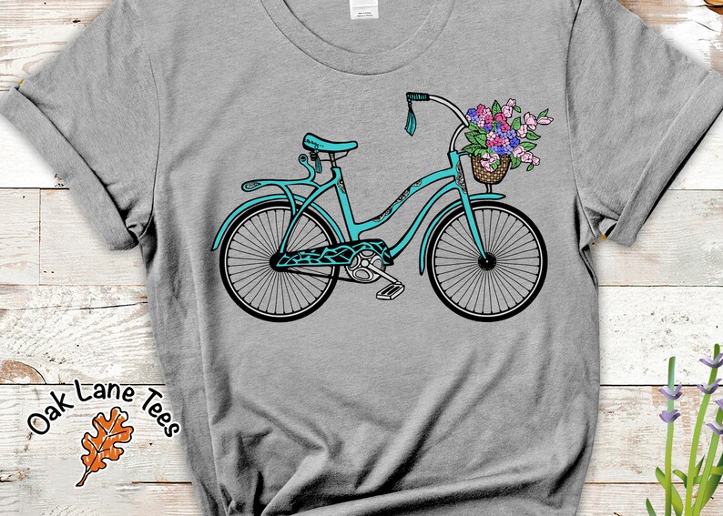 Puede incluir: Una bicicleta azul turquesa con una cesta de flores en el manillar. La bicicleta tiene un sill&iacute;n negro y neum&aacute;ticos negros. Las flores son rosas, moradas y blancas.