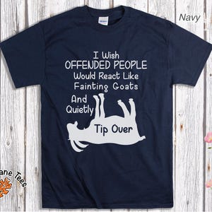 Może przedstawiać: Granatowa koszulka z białym napisem i grafiką omdlewającej kozy. Tekst brzmi: "I Wish Offended People Would React Like Fainting Goats And Quietly Tip Over." Koszulka pochodzi z Oak Lane Tees.