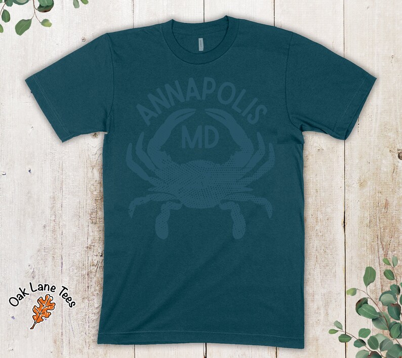 May include: Teal blue t-shirt with a distressed white graphic of a crab with the text "ANNAPOLIS MD" above it.