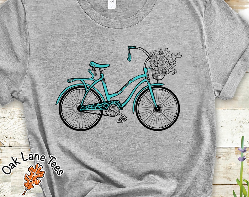 May include: A teal blue bicycle with a basket full of flowers. The bicycle has a white handlebar and a black seat.