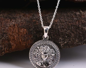 May include: Silver necklace with a round pendant featuring a detailed depiction of Medusa's face.