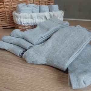 May include: A stack of gray socks folded neatly on a wooden surface.