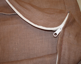 May include: A brown burlap bag with a white zipper. The zipper is open and the bag is folded over.