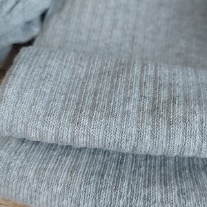 May include: Close-up of a gray knitted fabric with a ribbed texture.