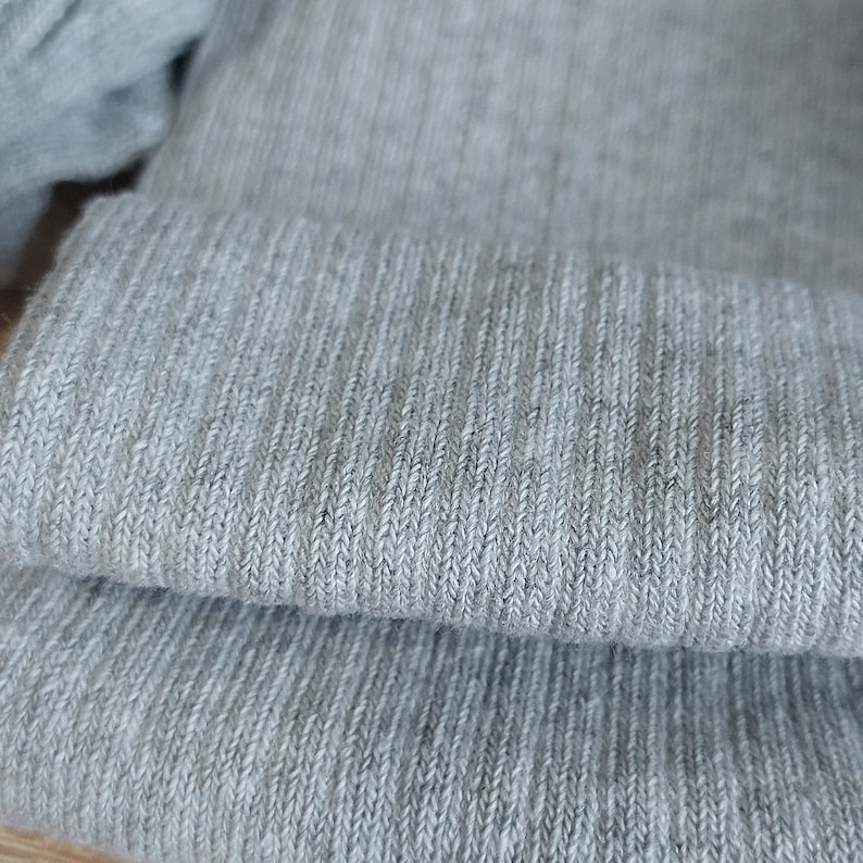 May include: Close-up of a gray knitted fabric with a ribbed texture.