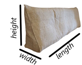 Puede incluir: Un cojín de respaldo de lino beige. El cojín es rectangular con un soporte triangular. La tela tiene un aspecto texturizado. El cojín está diseñado para brindar soporte lumbar al sentarse en la cama o en un sofá.