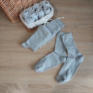 May include: A pair of gray socks with ribbed texture. The socks are folded and arranged in a wicker basket.