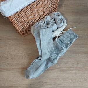 May include: A wicker basket filled with gray socks. The socks are folded and stacked neatly inside the basket.
