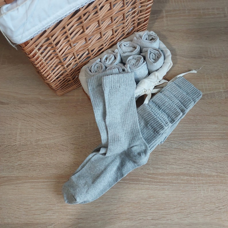 May include: A wicker basket filled with gray socks. The socks are folded and stacked neatly inside the basket.