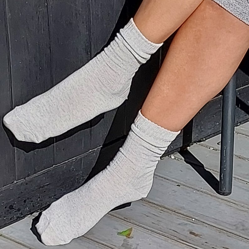May include: A pair of gray cotton socks with a ribbed texture. The socks are worn on a person's legs.