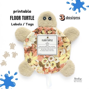 May include: A turtle-shaped fabric mat with a beige terry cloth head and four flippers. The shell features a floral pattern in shades of yellow, peach, and brown. A white tag attached to the centre reads: HANDMADE FLOOR TURTLE, with text about drips.