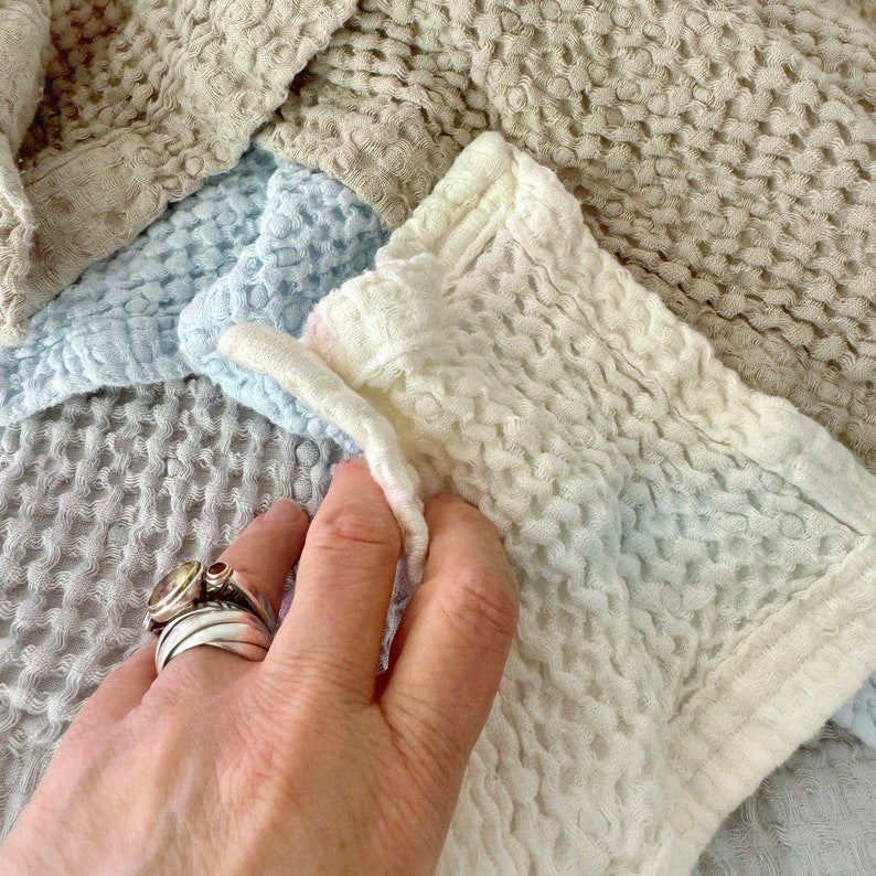 May include: A close-up of a waffle weave fabric in a variety of colors, including beige, light blue, and white. The fabric is soft and textured, and it is perfect for use in a variety of home decor projects.