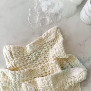 May include: A white waffle weave kitchen towel, folded and crumpled, with a textured surface. The towel is made of cotton and is soft and absorbent.