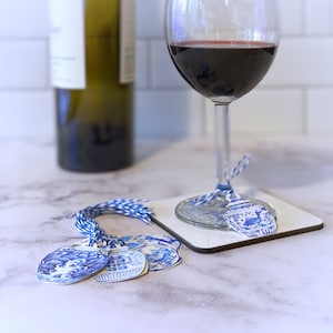 Puede incluir: Encantos para copa de vino de dise&ntilde;o de porcelana azul y blanco con una cuerda azul y blanca. Los encantos tienen forma de jarr&oacute;n peque&ntilde;o y cuelgan de una copa de vino tinto.