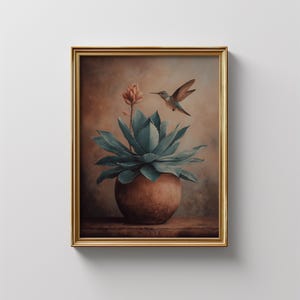 Puede incluir: Una impresi&oacute;n art&iacute;stica enmarcada que presenta una pintura a la acuarela de un colibr&iacute; que se cierne cerca de una planta suculenta en una maceta de terracota. La obra de arte tiene una paleta de colores c&aacute;lidos con tonos marrones, verdes y dorados.