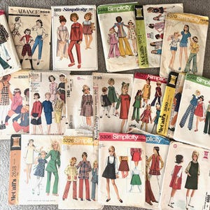 Pode incluir: Uma coleção de padrões de costura vintage para roupas infantis. Os padrões são das marcas Simplicity e McCall's e apresentam uma variedade de estilos, incluindo vestidos, saias, calças e blusas. Os padrões são de várias cores, incluindo vermelho, azul, verde e amarelo.