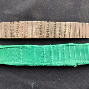 Puede incluir: Primer plano de un sello de metal con varios patrones y un sello de goma verde con los mismos patrones.