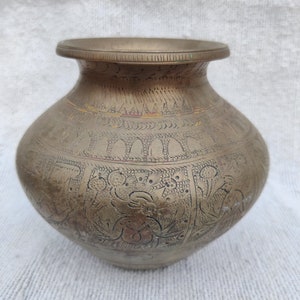 May include: A brass vase with intricate engraved designs. The vase has a rounded body and a wide mouth.