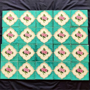 May include: A set of 20 turquoise blue ceramic tiles with a white and cream border. Each tile features a pink rose with green leaves in the center.
