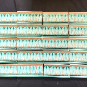 May include: A set of 20 teal green and cream colored ceramic tiles with a decorative pattern of stylized leaves and teardrop shapes. The tiles are arranged in four rows of five tiles each.