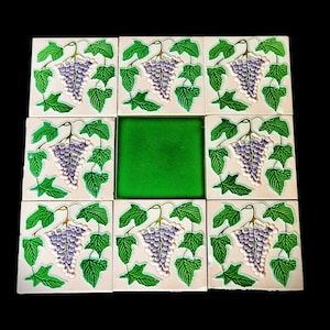 May include: Nine square ceramic tiles with a white background and green ivy leaves. Each tile features a cluster of purple grapes hanging from the ivy.