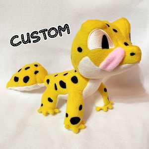May include: A yellow and black plush gecko toy with a pink tongue sticking out. The toy has a custom tag that says "CUSTOM".